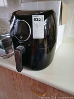 Black Habor air fryer with a transparent circular display window and handle shown from front and side views on a kitchen counter, with visible scratches and some dirt dust.