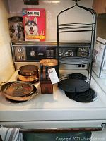 Three copper cookpots and black metal 3-tier plate tower on stovetop