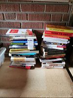 Two stacks of assorted leadership and business books against a brick wall.