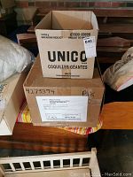 Two stacked cardboard boxes, one labeled UNICO and another plain with shipping label.