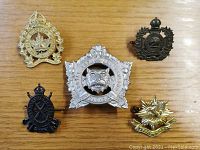 Top view of five military badges arranged on wooden surface showing details and color variations