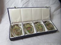 Four Chinese snuff bottles with painted scenes on the inside, presented in a fabric-covered box with white satin lining