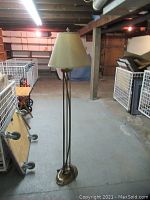 Full view of the brass-coloured standing floor lamp from base to shade, showing lamp height and structure.