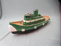 Front angle view showing the green hull with white bumpers and textured white bow.