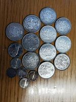 Fifteen silver coins of mixed denominations arranged on wooden surface