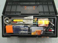 Open toolbox showing tools inside including caulking gun, trowel, screwdrivers, and boxes of staples.