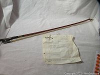 Full view of cello bow and receipt on white background