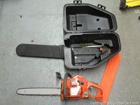 Overall view of chainsaw, carry case open, bar scabbard and tool
