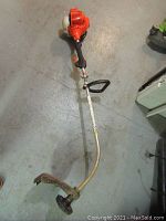 Full view of Echo string trimmer showing engine housing, straight shaft, handle and cutting head on concrete floor