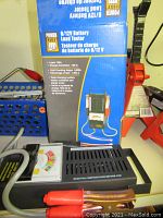 Power Fist 6/12V battery load tester with attached cables and original box showing product details.