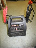 Front view showing Terminator Mobile Power Pack unit with handle, alligator clamps attached, and control panel with testing and charging functions.