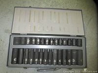 Opened metal case displaying organized set of ratchet sockets with size markings visible on each socket.