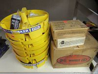 Photo showing multiple yellow stackable trays filled with assorted nails, screws, and hardware next to labeled cardboard boxes.