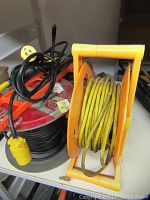 Photo showing yellow cable on a yellow plastic reel next to other cables.
