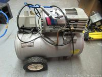 Side view of compressor showing tank, wheels, motor, pressure regulator and attached hose