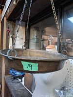 Close-up of the brass hanging cradle suspended by chains, showing the round shape and diameter of about 10 inches.