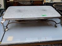 Full view of the rectangular silver plated warming tray with its four feet and raised edges, showing the top surface with minor scratches and tarnish.