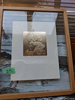 Framed embossed print showing the full artwork with a profile of a face and other detailed elements.