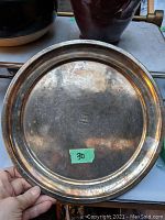 Top view of silver service tray showing surface scuffs and scratches with a small green sticker