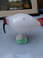 Front view of white glass kiwi bird on pedestal