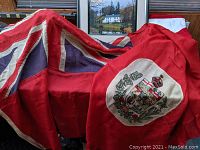 Draped full flag showing red field, Union Jack canton and coat of arms panel