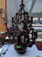 Front view of the dark brown ceramic peacock candelabra showing multiple candle holders and detailed curled tail feathers.