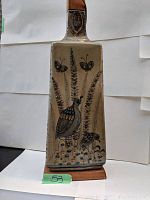 Front view showing bird and butterfly motif on ceramic body with wooden base