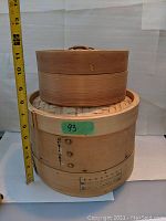 Two bamboo steaming baskets stacked, large one 10 inches diameter, medium one 7 inches diameter with lids, close up view.