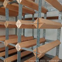 Close-up of the wooden bottle holders with diamond-shaped ends and metal frame of one wine rack.