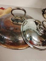 Two lids side by side; polished small lid and tarnished large lid engraved “Canadian Pacific”