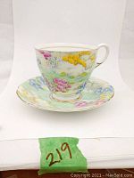 Photo showing the full teacup on the saucer from a side angle revealing floral pattern and gold trim.