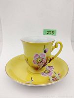 Yellow demitasse tea cup with cherry blossom painting and matching saucer, marked 'Made in Occupied Japan' on base.