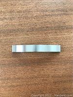 Top-down view of a single brushed nickel cabinet handle showing the brushed finish and straight clean lines.