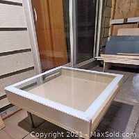Square IKEA coffee table with birch wood frame and glass top, showing surface and lower shelf.