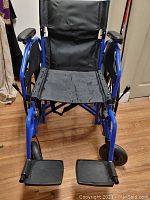 Front view of wheelchair without cushion showing black nylon seat and footrests