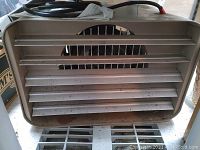 Front view showing beige metal heater with horizontal adjustable baffles for airflow control.