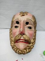 Front view of the hand carved and painted wood ceremonial dance mask showing detailed facial features and gold-painted hair and beard.