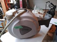 Side view of the off-white FloMaster hose reel showing the length and shape of the unit with hose attached.