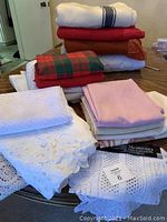 Stacked vintage wool blankets and various folded linens in different colors and textures