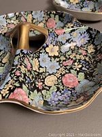 Close-up of the floral pattern interior and gold trim of one three-part candy dish with visible chip on edge