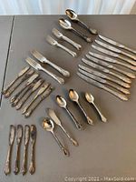 Full overview of the cutlery set including knives, forks, spoons, and butter knives laid out on table.