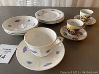Photo of two Capodimonte demitasse teacups and saucers, one Adderley Blue Chelsea cup, four matching saucers, and four plates with blue floral patterns.