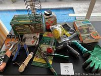 Photo showing an assortment of garden hand tools, pruning shears, a bird feeder cage, garden hose nozzle, gloves, and a box of bird seed.