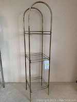 Full view of tall brass shelf with bamboo styled frame and three shelves