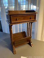 Full view of wooden telephone table with drawer and magazine rack showing overall design and finish.