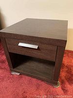 Dark wood square side table on red carpet showing front with closed drawer and open lower shelf