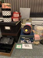 Photo showing a variety of decorative empty boxes including round nesting boxes, patterned gift boxes, and storage boxes stacked on a surface