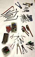 Overview photo showing a large collection of hand tools including crowbars, wrenches, pliers, screwdrivers, and hex keys spread out on a surface.