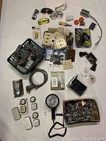 Overview of assorted electrical boxes, switches, wall plates, goggles, a soldering gun, electrical cords, and DC searchlight light