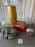 Photo showing all five items including three flower vases and two tins arranged on a table with sheer curtains in the background.